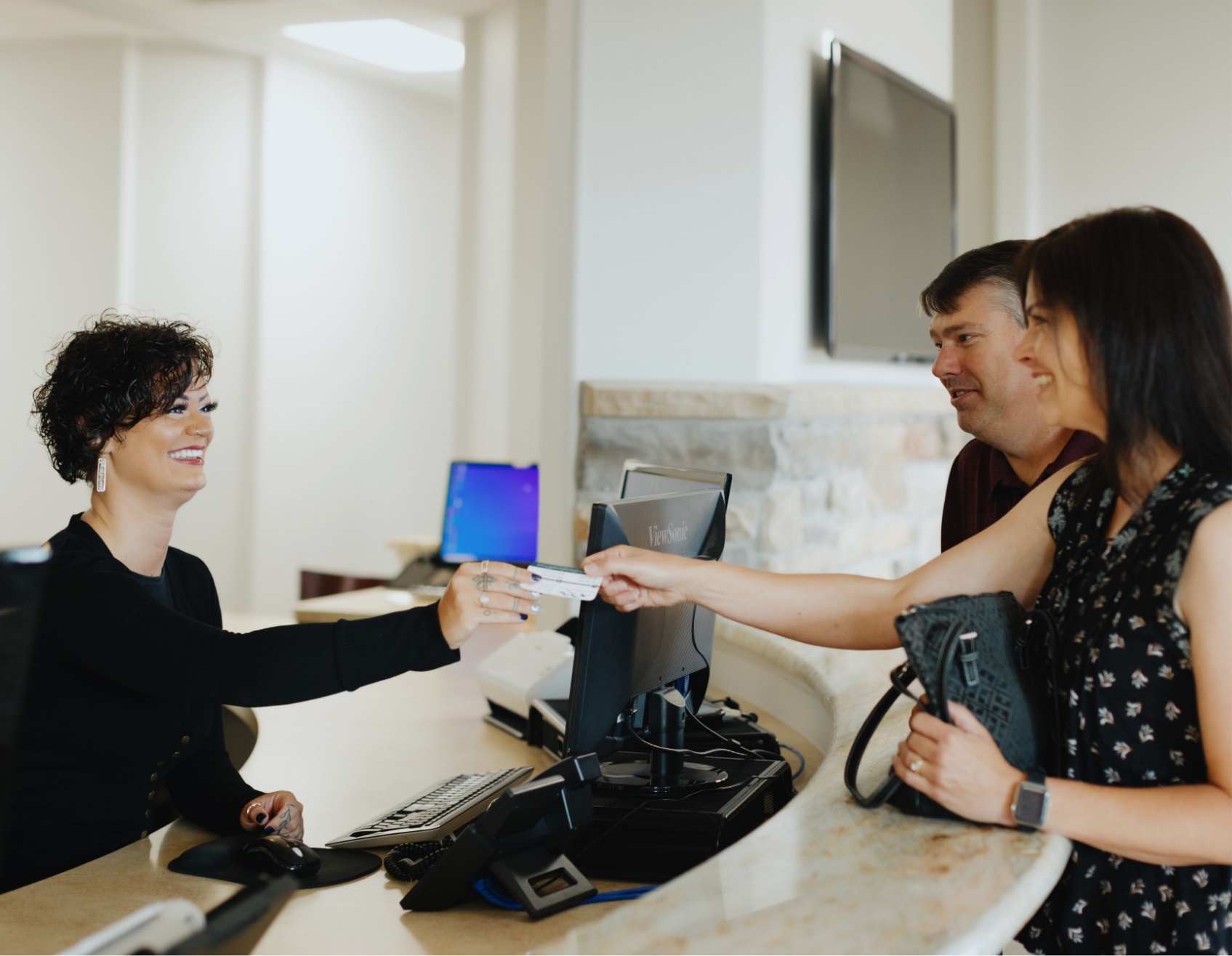 a woman greeting two patients into the building