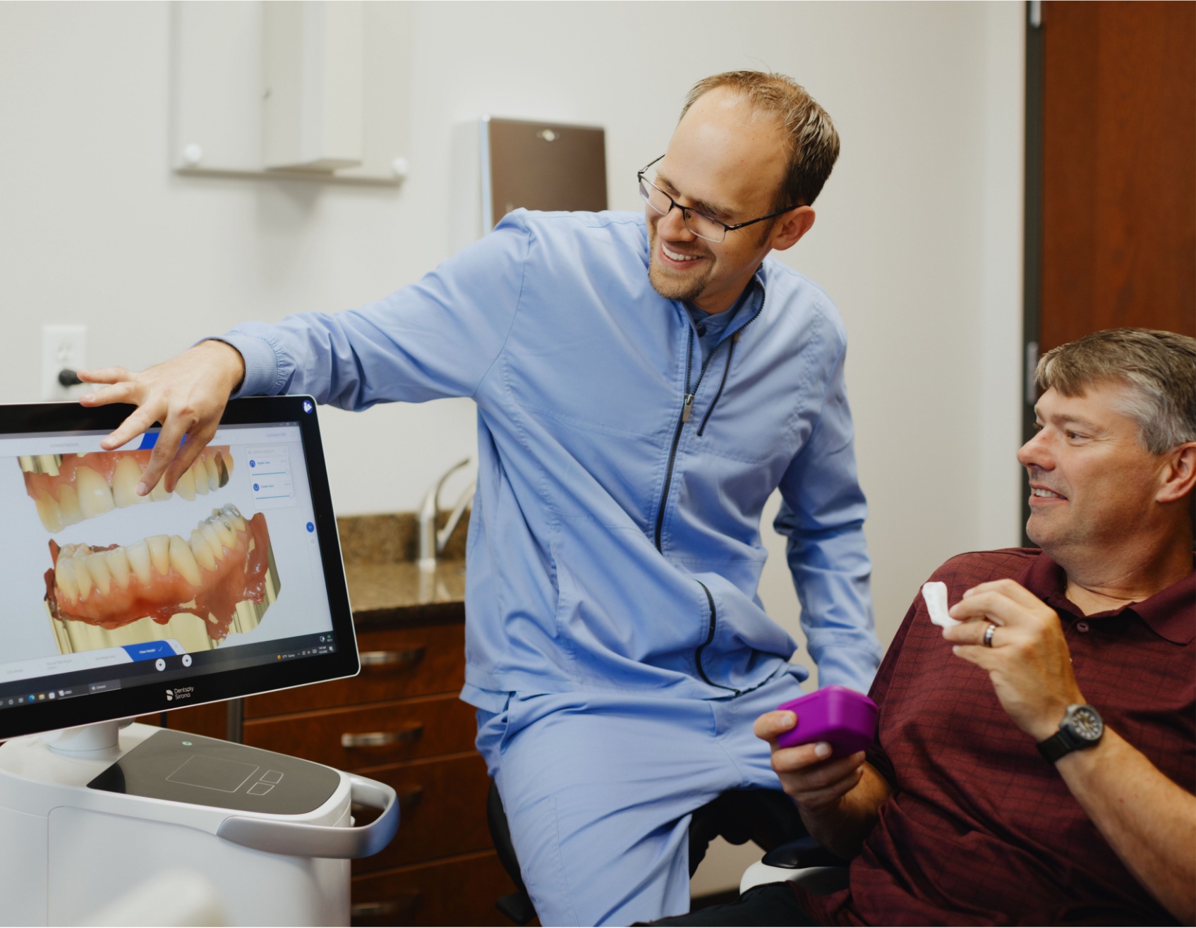 Dr. Adam Milmont smiling and showing something on the computer to a patient