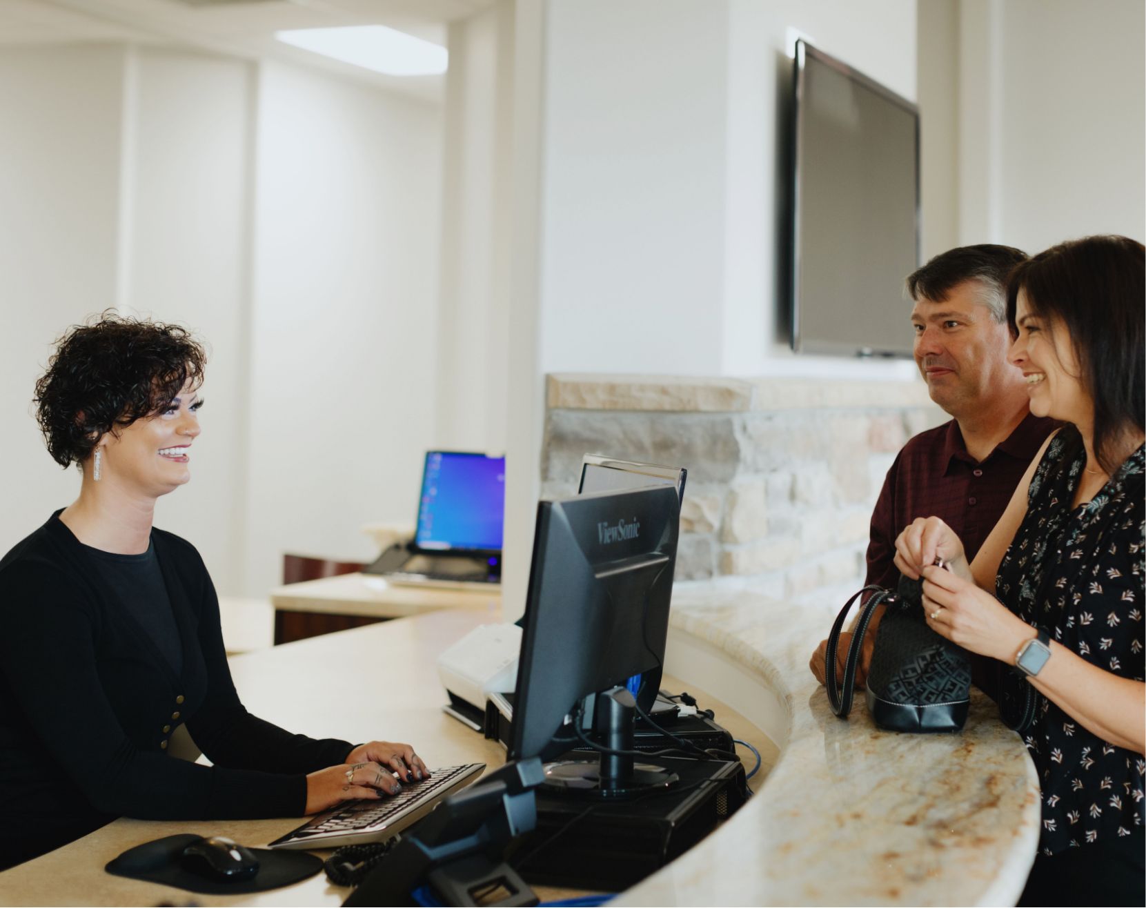 a women greeting two patients at Hilltop Family Dental